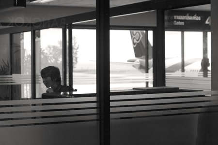 PHUKET INTERNATIONAL AIRPORT, PHUKET, THAILAND JULY 15 2012: A passenger checks his tablet while waiting to board a flight.のeditorial素材