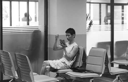 PHUKET INTERNATIONAL AIRPORT, PHUKET, THAILAND JULY 15 2012: A passenger checks his tablet while waiting to board a flight.のeditorial素材