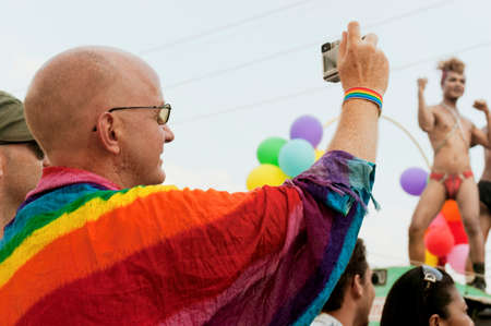 PATONG, PHUKET, THAILAND, 26 FEBRUARY 2011: A tourist wrapped in a rainbow flag snaps a photo during the annual Patong Gay Pride Parade.のeditorial素材