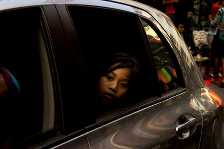 PATONG, PHUKET, THAILAND, 26 FEBRUARY 2011: A young girl watches a post-parade celebrationfrom the backseat of a carparty in Soi Paradise at the annual Patong Gay Pride Parade .のeditorial素材