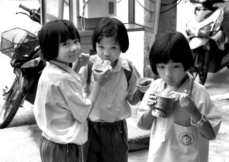 PHUKET, THALAND, 22 AUGUST 2011: Three Thai schoolgirsl enjoy instant noodles after school.のeditorial素材