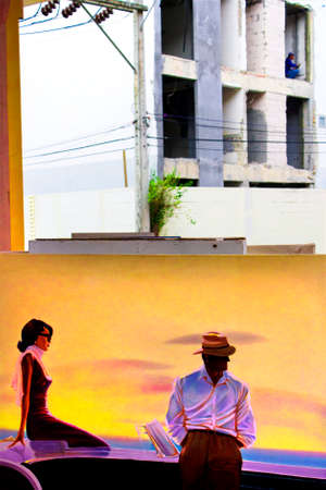 PATONG BEACH, PHUKET, THAILAND, 18 AUGUST 2009: A construction worker does his job above a painting on display at an outdoor gallery.のeditorial素材