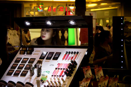 JUNGCEYLON MEGAMALL, PHUKET, THAILAND, 27 DECEMBER 2013: A Thai woman tries on some make-up at a kiosk in a shopping center.のeditorial素材