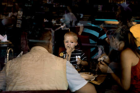 PHUKET, THAILAND, 1 MARCH 2012: Boy on holiday enjoys Thai food at restuarnt with mom and dad.のeditorial素材
