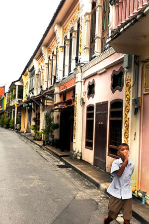 SOI ROMANEE, OLD TOWN PHUKET, PHUKET, THAILAND, 6 JULY 2012: Schoolboy enjoys a drink after school on Soi Ramonee.のeditorial素材