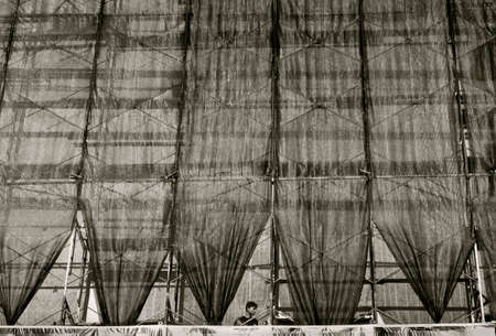 PHUKET, THAILAND, 26 AUGUST 2013: A worker stands under construction site screens at a construction site in Phuket.のeditorial素材