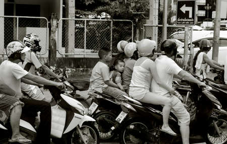 PHUKET, THAILAND, 18 MAY 2012: Toddler on scooter waits for red light with brother and mother.