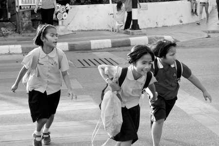 PHUKET, THAILAND, 15 FEBRUARY 2012: A group of Thai school girls run across the street at the end of the school day.のeditorial素材