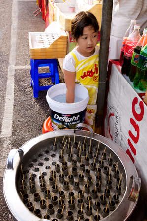 PHUKET VEGETARIAN FESTIVAL, PHUKET, THAILAND, 30 SEPTEMBER 2012: A girl sells popsicles on the eve of the annual Phuket Vegetarian Festival.のeditorial素材