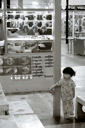 UDON THANI, THAILAND, 15 JULY 2012: The daughter of a food vendor at a night market plays past her bedtime.のeditorial素材