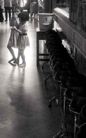 WAT PHO, BANGKOK, THAILAND, 26 SEPTEMBER 2014: Two sisters prepare to throw coins into donation bowls inside a temple building at Wat Pho in Bangkok.のeditorial素材