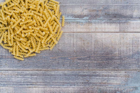 a lot of pasta on a wooden background, stacked in a bunch, place for text, for a logo