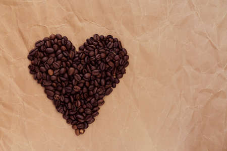 coffee beans in the shape of heart on old paper, background for text
