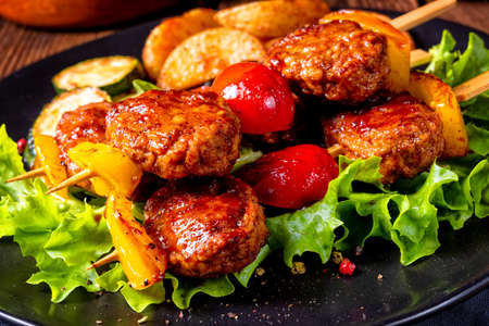 rustic Meatballs skewers of tomato, paprika and baked potato quartersの写真素材