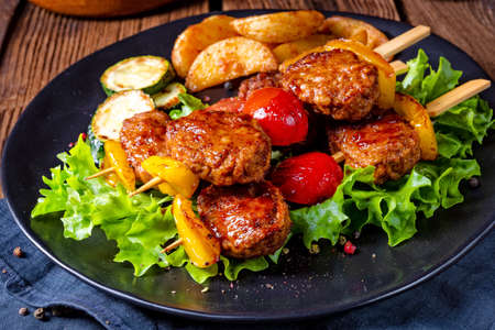 rustic Meatballs skewers of tomato, paprika and baked potato quartersの写真素材