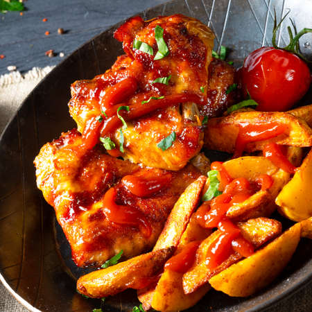 Rustic chicken wings in honey with potato wedgesの写真素材