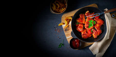 Spicy chicken wings in honey with potato wedgesの写真素材