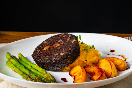 Black pudding with green asparagus and fried appleの写真素材