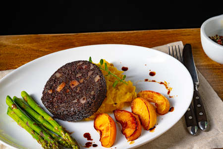 Black rice with asparagus and peaches on a white plate