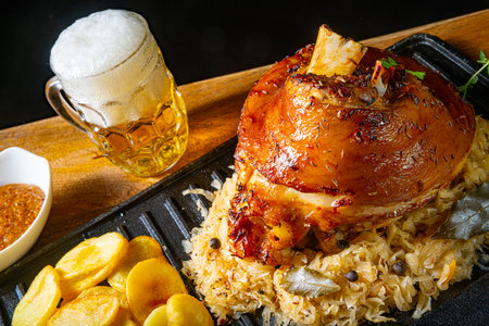 rustic pork knuckle with sauerkraut, sweet mustard and fried potatoesの写真素材