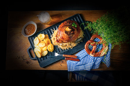 rustic pork knuckle with sauerkraut, sweet mustard and fried potatoesの写真素材