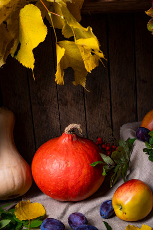 Various fruits in a wooden box with autumn leavesの写真素材