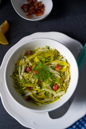Zucchini salad with bacon and dill in a white bowlの写真素材