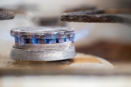 Close-up shot of flame of burning gas stove with metal setting above