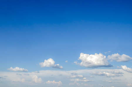 White fluffy clouds flying in the deep blue summer sky, view from the planeの写真素材