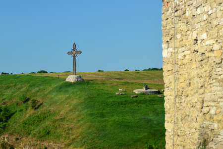 Old metal cross standing near medieval fortress wallの写真素材