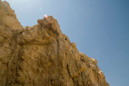 Mountains in Israel stone desert, photo with lens flare natural effect. Bird sitting among stones of mountaintopの写真素材
