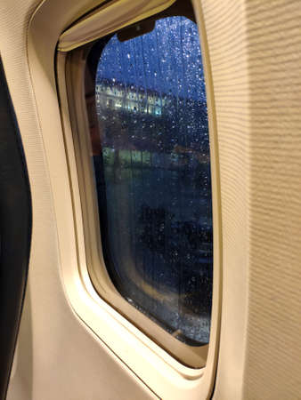 Airplane window close view. Rainy weather outside before take off