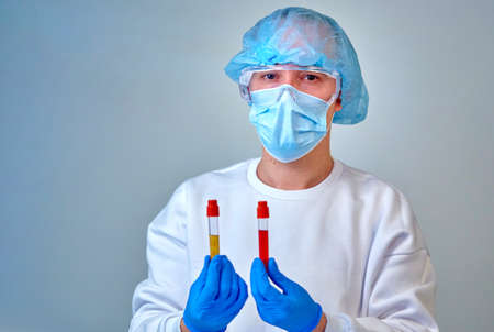 Doctor in mask holding the blood test tubes, coronavirus COVID19, HIV, ebola or other dangerous...