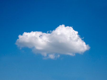 Single white cloud over blue sky background. Fluffy cloud shape photoの写真素材