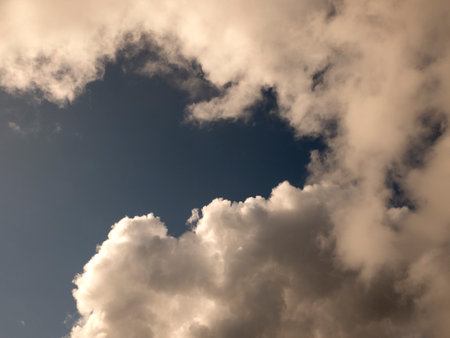Fluffy clouds over sunset sky. Fluffy cumulus cloud shape photo, gloomy cloudscape background, smoke in the skyの写真素材
