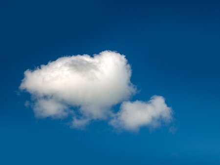 Single white cloud over blue sky background. Fluffy cumulus cloud shapeの写真素材