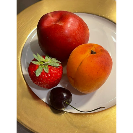 Ripe apricots, strawberries and cherries on a white plateの写真素材