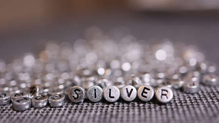 Silver letters on beads on a silver background.の写真素材