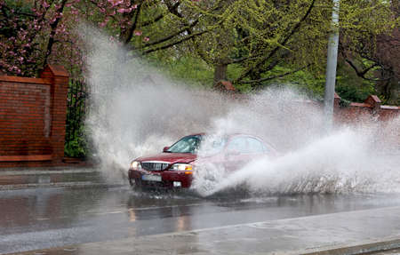 The car falls into a pool of water on the road, causing a splash.の写真素材