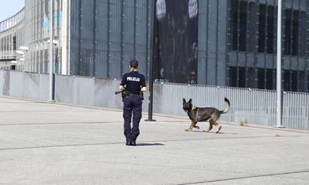 A policewoman guides a service dog on patrol with her partner.のeditorial素材