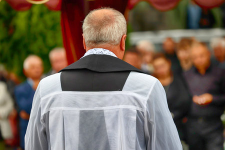 A Catholic priest in a surplice with a purple table during a funeral celebration. Rite