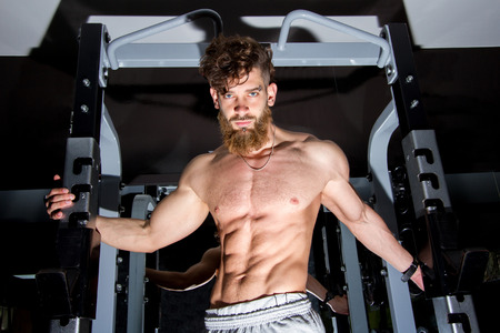 Muscular man with the beard posing in the gym