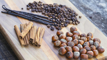 Vanilla and cinnamon sticks,with coffee beans and hazelnuts on wooden board