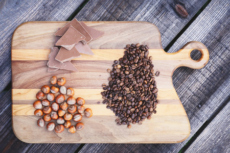 Hazelnuts,chocolate and coffee beans on wooden boardの写真素材