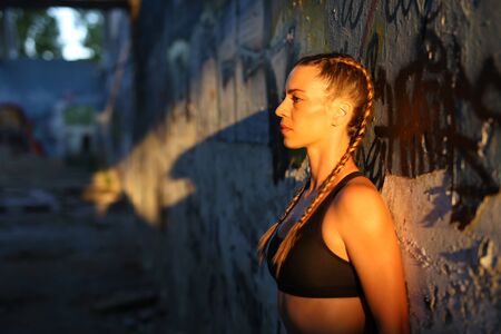 Attractive girl with hair braids posing in  low sunlight and shadowsの写真素材