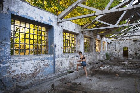 Fitness girl getting ready for training in abandoned ruined factory buildingの写真素材