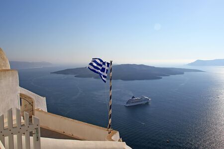 View on the volcano with Greek flag in front,Santorini island,Greeceの写真素材