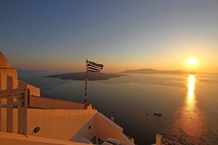 View on the volcano in sunset with Greek flag in front,Santorini island,Greeceの写真素材