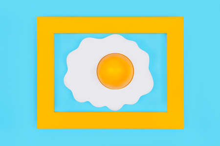 Fried egg in yellow frame on pastel blue background,minimal konceptの写真素材