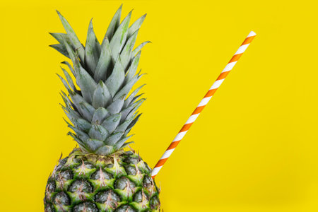 Pineapple with straw on yellow background. Fresh juice creative concept.